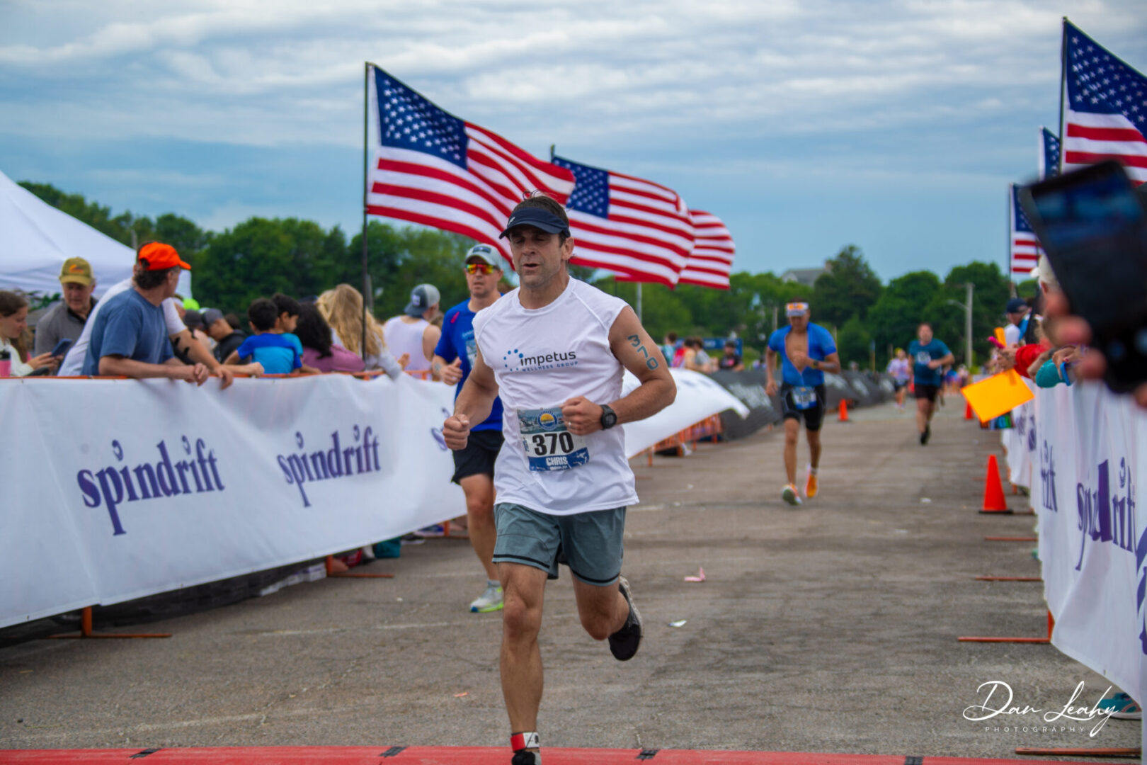 Runner crossing finish line with American flags